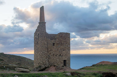 Castle by sea against sky during sunset