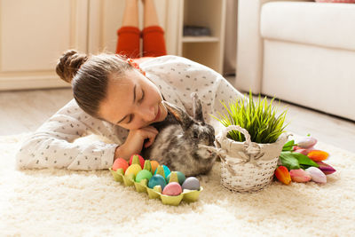 Woman playing with rabbit while lying at home