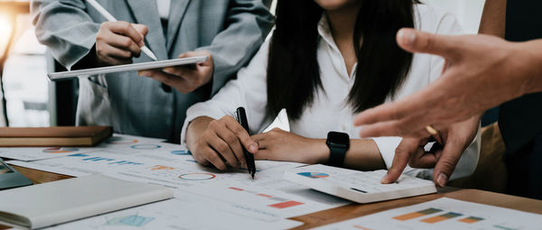 Midsection of business colleagues working on table