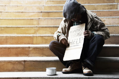 Male beggar begging while sitting on steps