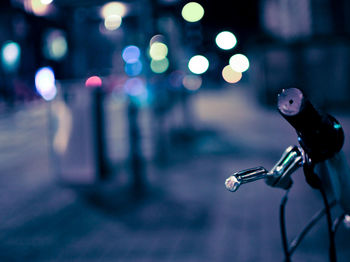 Close-up of bicycle on illuminated city street at night