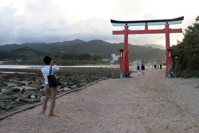 Rear view of people walking on mountain against sky