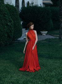 Woman standing on grass against trees