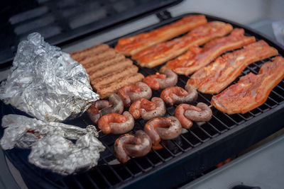 High angle view of meat and sausages on barbecue grill