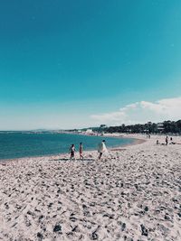 People on beach against blue sky