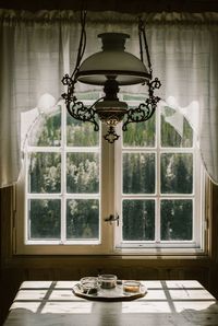 Illuminated lamp on table by window at home