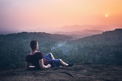 Man looking at mountains against orange sky