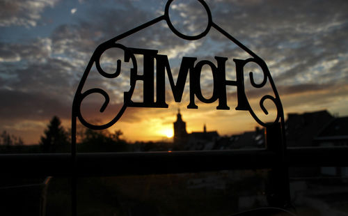 Close-up of text on glass window against sunset sky