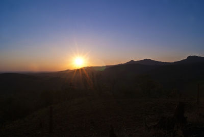 Scenic view of silhouette mountains against clear sky during sunset