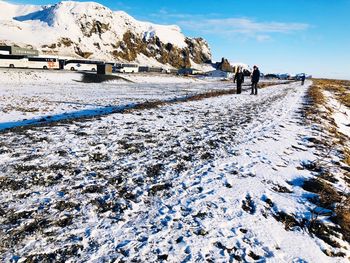 People walking on snow covered mountain against sky