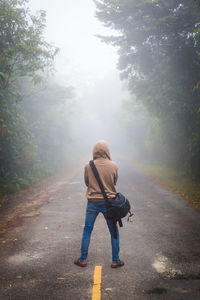 Rear view of man with bag standing on road