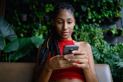 Young woman using mobile phone while sitting in park