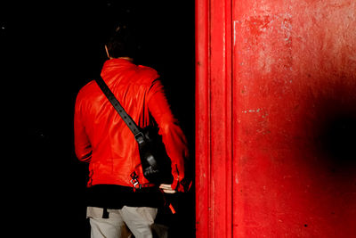 Rear view of man next to red phone booth 