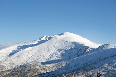 Scenic view of snowcapped mountains against clear blue sky