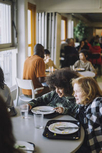 Curious friends sitting at table during lunch break at school cafeteria