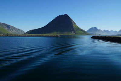 Scenic view of sea and mountains against clear blue sky