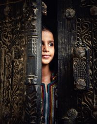 Portrait of young woman standing against door