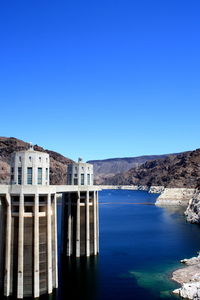 Scenic view of river by buildings against clear blue sky