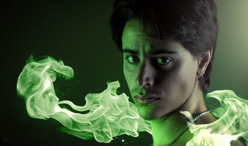 Close-up portrait of man with flame against colored background