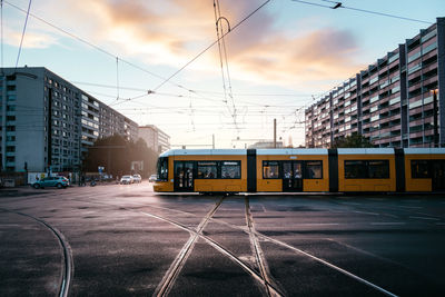 Cable car on city street by buildings against sky