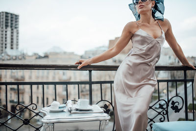 Midsection of woman standing by railing against sky