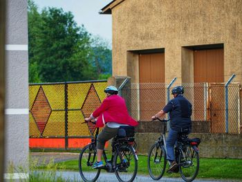 Rear view of people riding bicycle against building