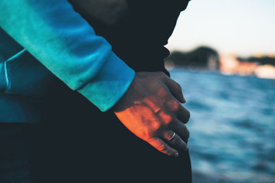 Close-up of man hand holding sea against sky