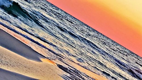 Close-up of sea against clear sky at sunset