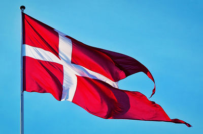 Low angle view of flag against blue sky