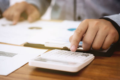 Midsection of man holding paper with text on table