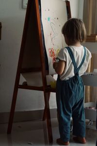 Rear view of boy painting at home