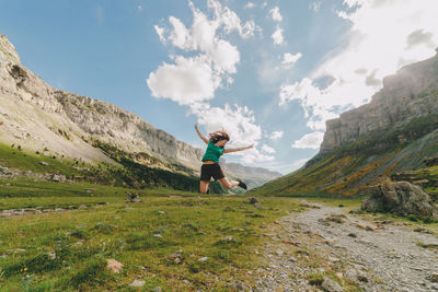 Woman jumping against mountains on field