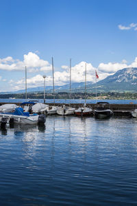 Boats moored at harbor against sky