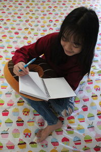 High angle view of girl studying while sitting on floor at home