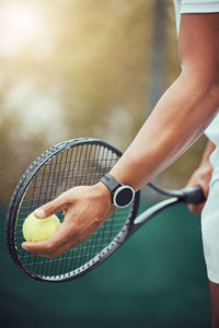 Midsection of man holding tennis