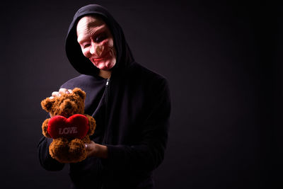 Portrait of man holding toy against black background