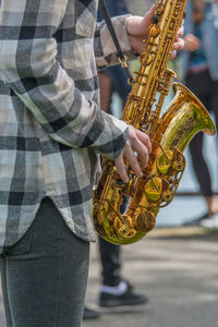 Midsection of street musician playing saxophone