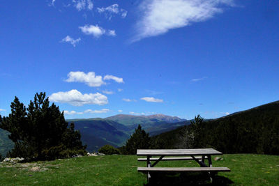 Bench in park against blue sky