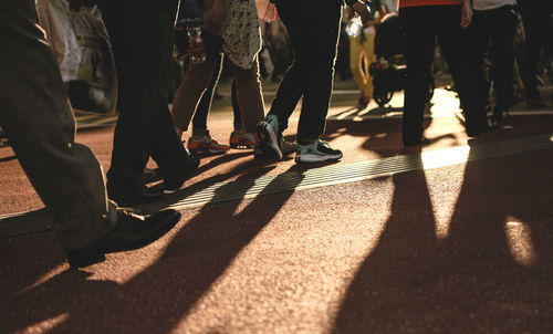 Low section of people walking on street in city