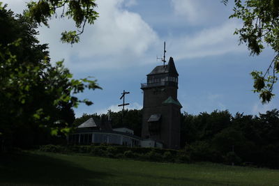 Built structure by trees and building against sky