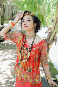 Portrait of young woman standing against wall