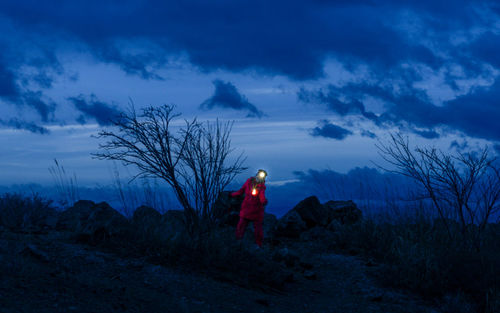 Rear view of woman standing on mountain against sky