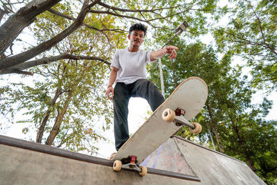 Low angle view of boy standing on tree