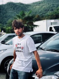 Young man looking at camera while standing in car