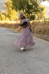 Rear view of woman with hat on road