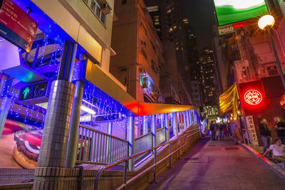 Illuminated street amidst buildings in city at night