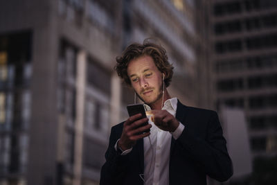 Businessman in the city at dusk using cell phone