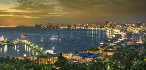 High angle view of illuminated buildings by sea against sky