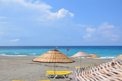 Deck chairs on beach against sky