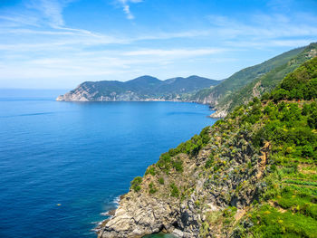 Green mountains by sea against sky